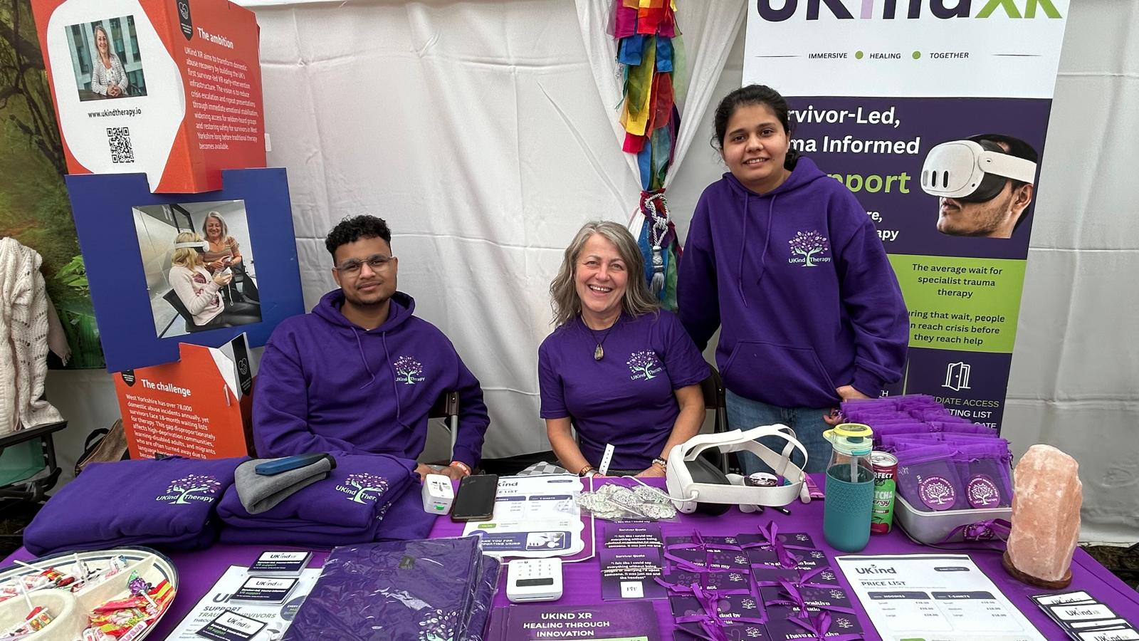 Three members of the UKind team at the UKind XR event stand with headsets and materials
